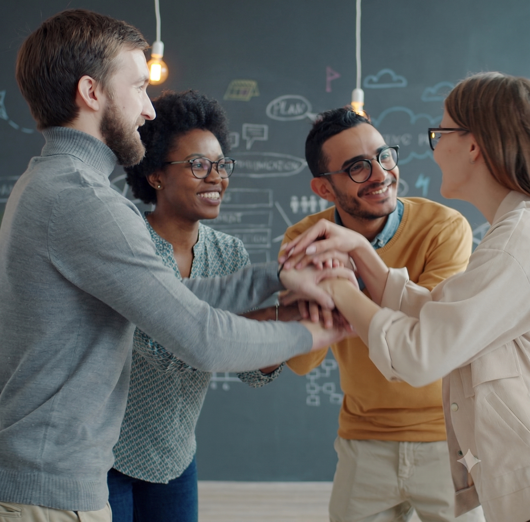 Coworkers putting hands together in a team huddle